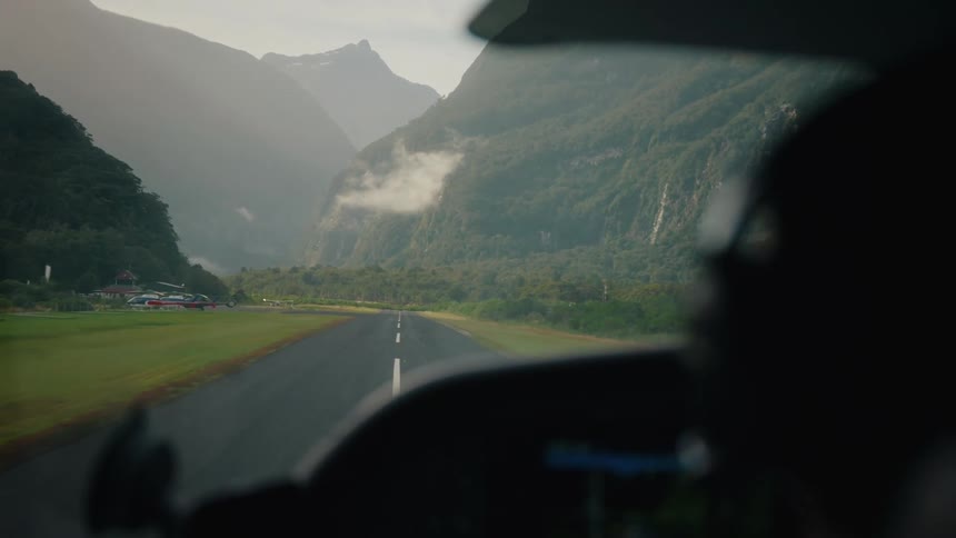 View from the cockpit of a small plane as it accelerates down a runway for takeoff in a remote, mountainous valley