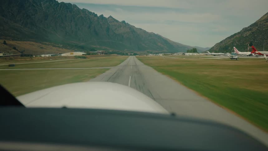 Point of view from inside a small plane as it accelerates down the runway and takes off from an airport nestled in a scenic mountain valley