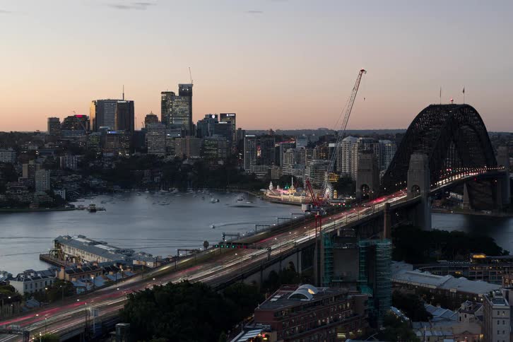 An epic day-to-night timelapse shows traffic streaming across the iconic Sydney Harbour Bridge as the city lights up