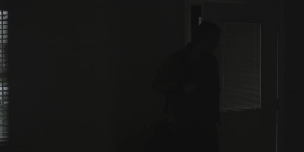 A man carrying a bag over his shoulder enters a room from the outside