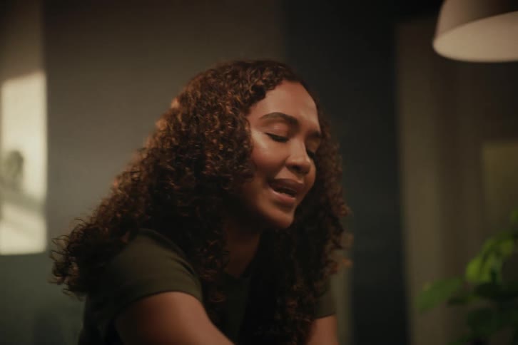 An emotional young woman with curly hair finds a moment of peace and relief, smiling through her tears
