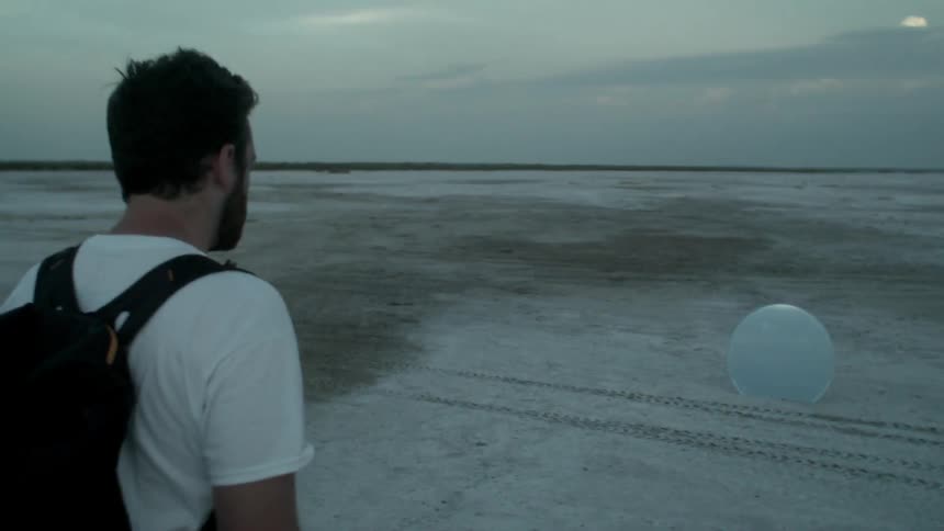 A man approaches a mirror in the desert