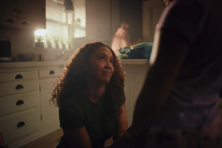 A loving mother shares a tender moment with her child, holding their hands in a warm, sunlit kitchen