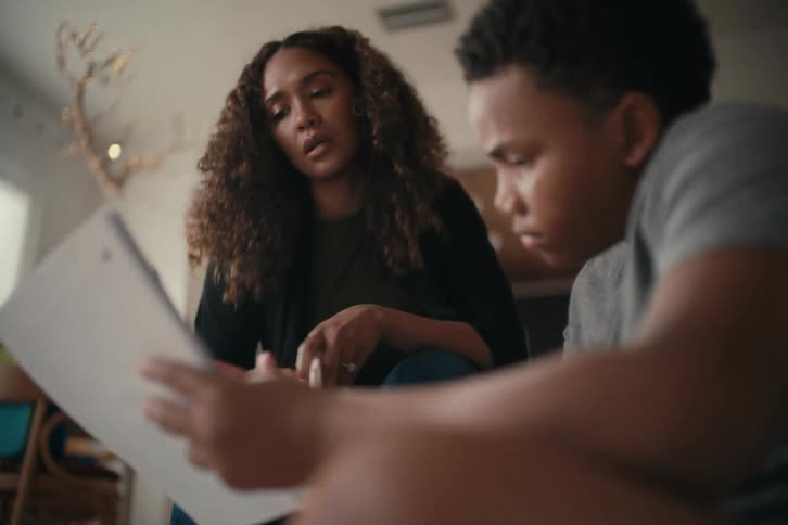 A caring mother sits with her son to patiently help him with his challenging homework in their home