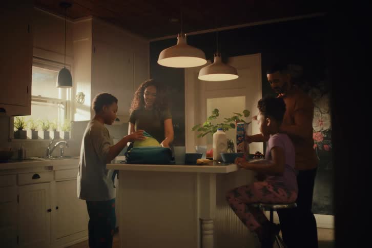 A loving family of four shares a happy morning routine in their cozy, sunlit kitchen