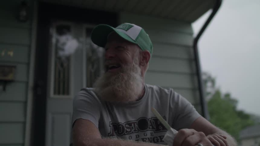 A man laughs while sitting on the front steps of a house