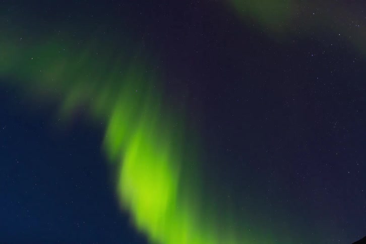 Vibrant green northern lights dance across the starry night sky in this stunning time-lapse