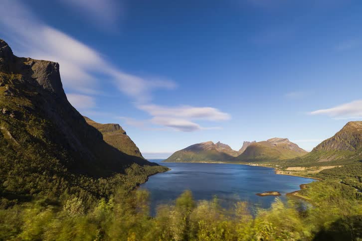 A majestic time-lapse captures clouds moving over a sunlit Norwegian fjord surrounded by mountains