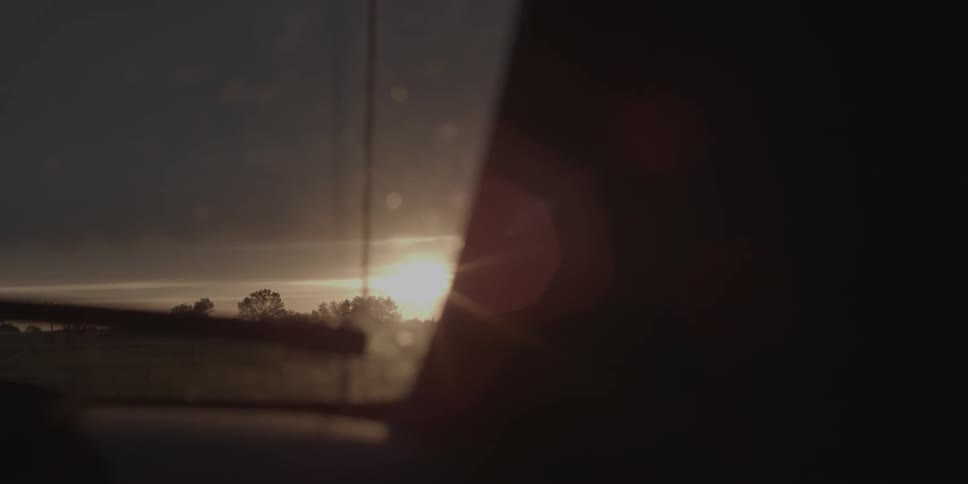 Sunlight shines on a car windshield at sunset