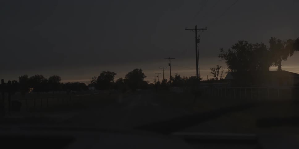 A car drives down a road at dusk