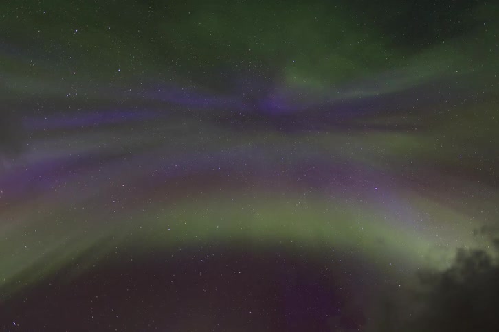 A mesmerizing time-lapse of the purple and green Northern Lights dancing across a star-filled night sky