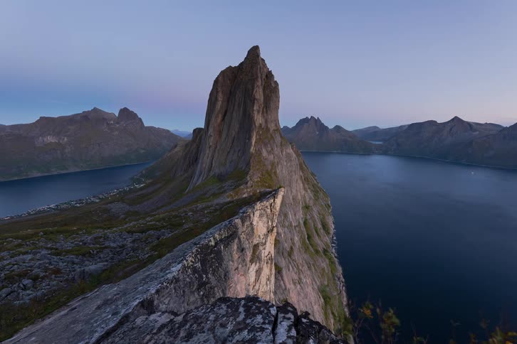 A stunning sunset-to-night-sky timelapse over the iconic Segla mountain in Norway, revealing a glowing coastal village and the ethereal aurora borealis