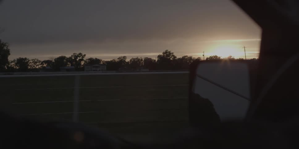 A car drives in a rural area at sunset