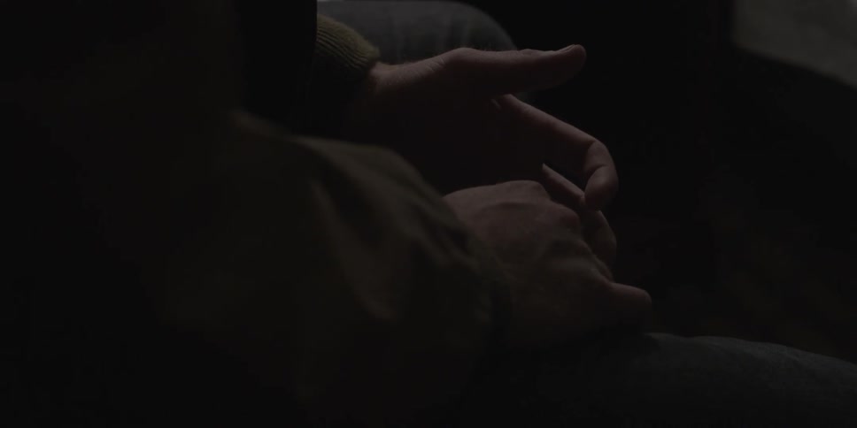 A person fidgets with their fingers while sitting in the dark