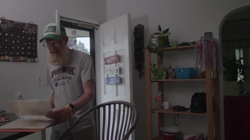 A man is standing near a table reading a paper