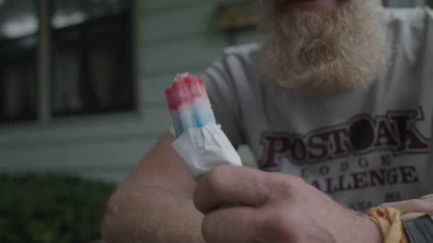 Man sits on his porch holding a popsicle