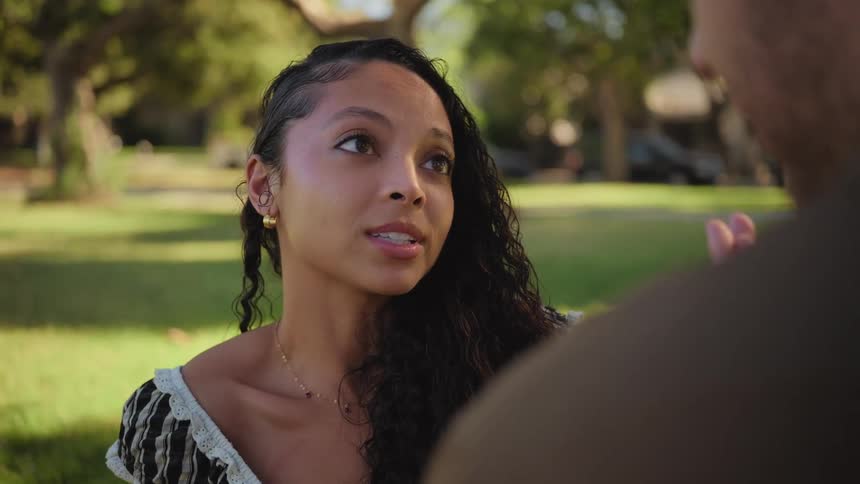 Close-up of a beautiful young woman listening attentively and smiling during a romantic conversation in a sunny park
