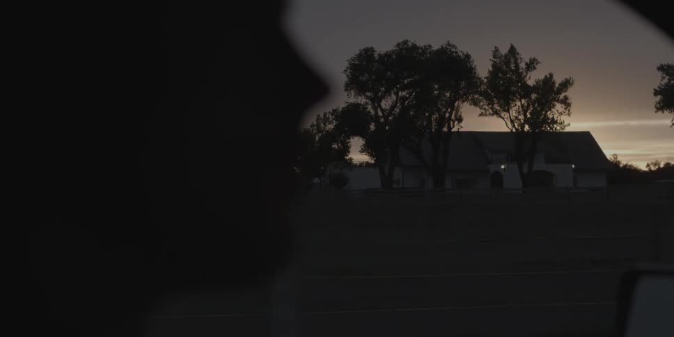 A house sits on a dark field at dawn