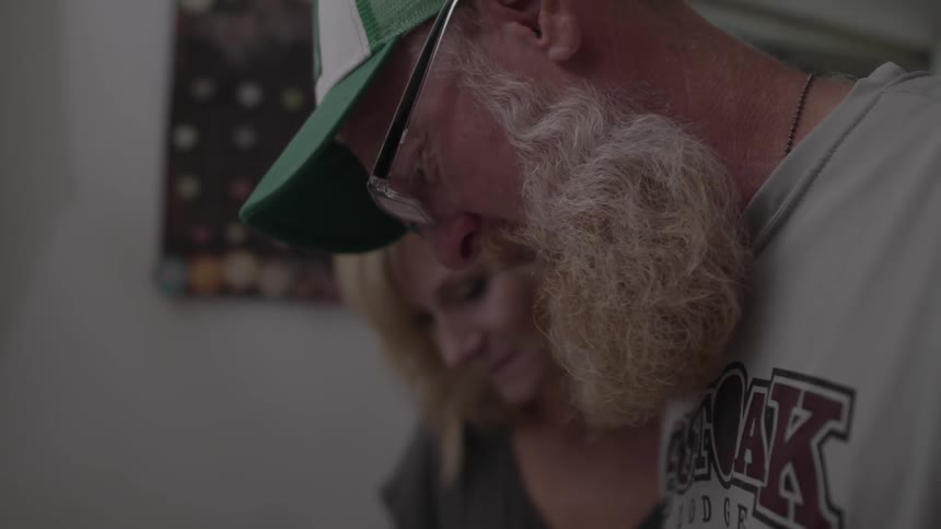 A man and woman talk while looking downward