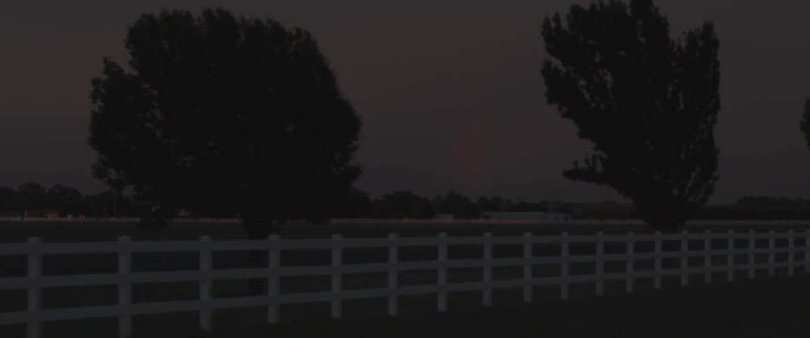White, wood fencing is seen on a property alongside a road