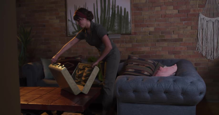 A female archeologist enters her apartment with a special case and begins to sort through her recent discovery of ancient bones