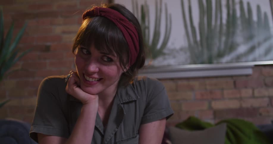 An intimate portrait of a woman with a red headband smiling warmly as she listens intently in a cozy room
