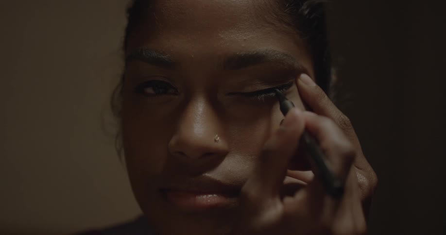 A woman applies eyeliner to her eyelid