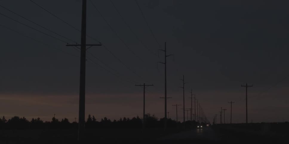 The road is dark with power lines on the side of the road