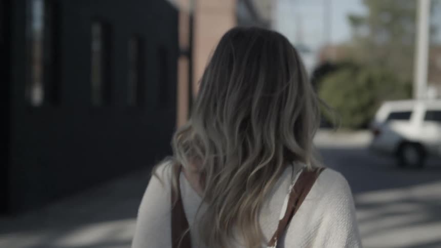 A woman walks on a city sidewalk