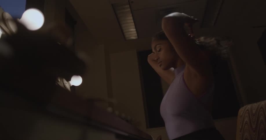 Dancer secures her hair at the nape of her neck