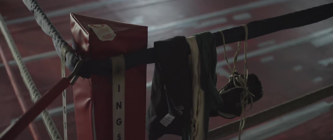 Boxing gloves and garment hanging on boxing ring rope