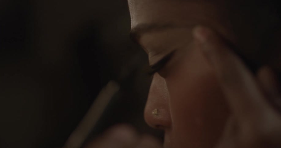 A woman applies eyeliner to her top lid
