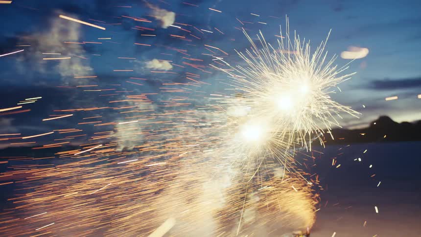 A woman watches a fountain of fireworks erupt with a shower of sparks on the vast salt flats at twilight