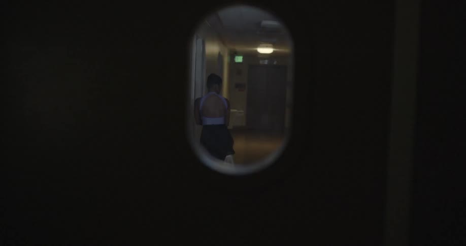 A woman walks across the hallway stretching her arms