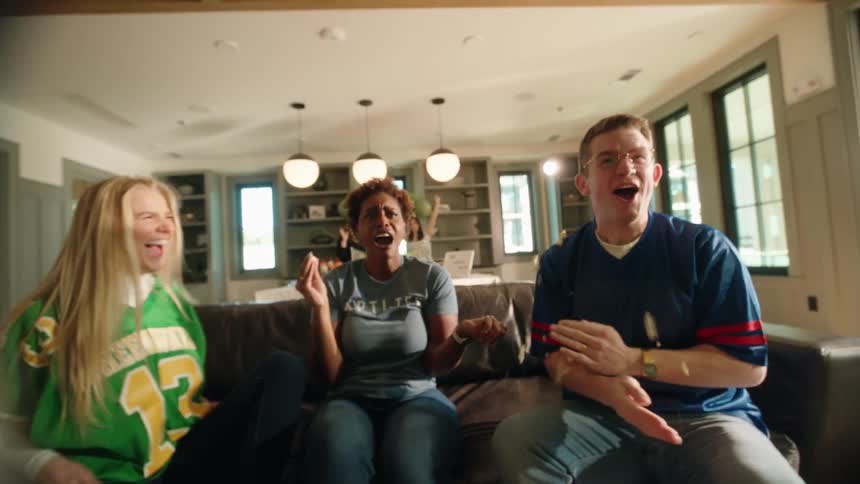 Ecstatic group of friends celebrate a sports victory at home, cheering and throwing popcorn in the air in slow motion