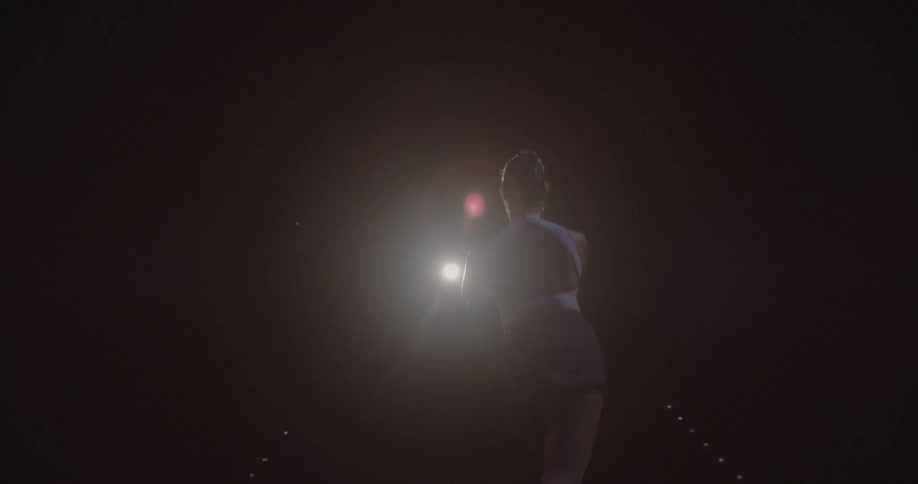 Woman dancing ballet on dark stage with one light shining on her