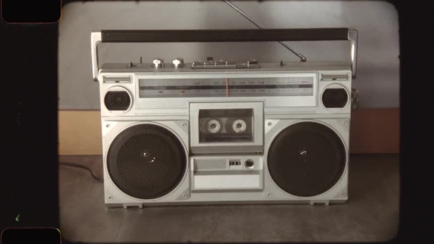 A retro cassette tape plays inside a vintage boombox, with the camera zooming out to reveal the full stereo in a nostalgic film style