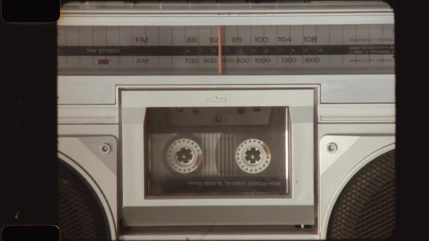 Close-up of a vintage cassette tape playing in a retro ghettoblaster with an old film aesthetic