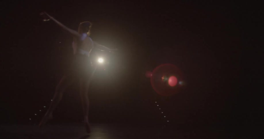 Woman dancing a ballet in a dark room with a few lights