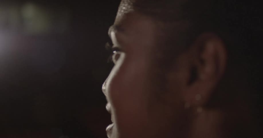 A light shines on a smiling woman's face