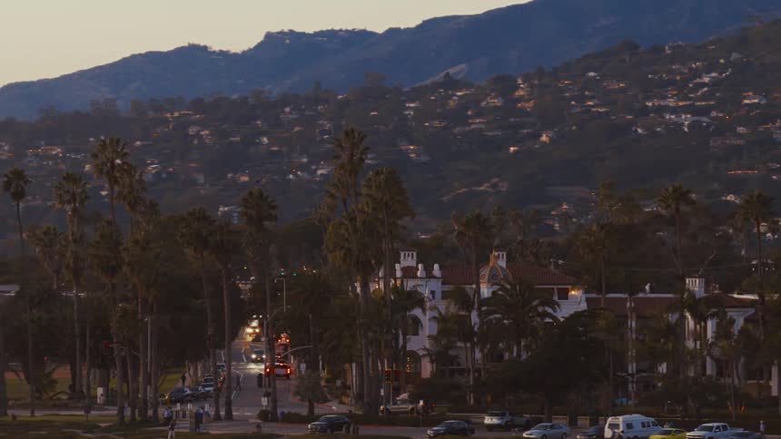 A scenic view of Santa Barbara's palm tree-lined streets and mountain homes at sunset