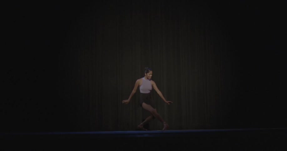 A woman jumps out onto a dark stage