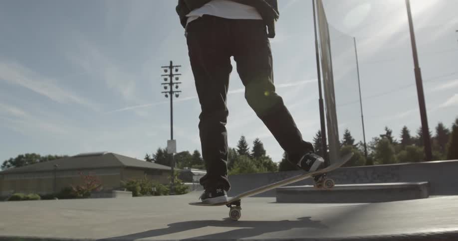 Man riding skateboard on ramp in skate park on sunny day