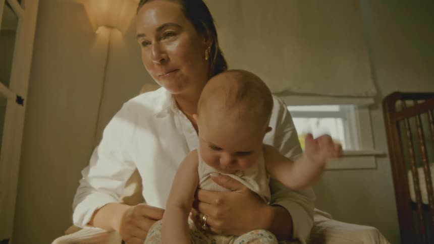 A loving mother holds her baby on her lap, sharing a tender and happy moment in a sunlit room