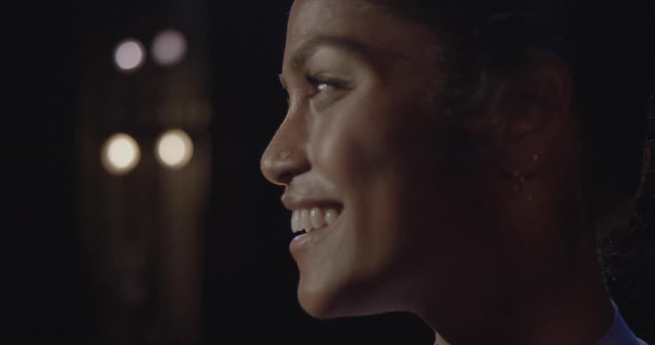A woman is standing amid stage lights and smiling