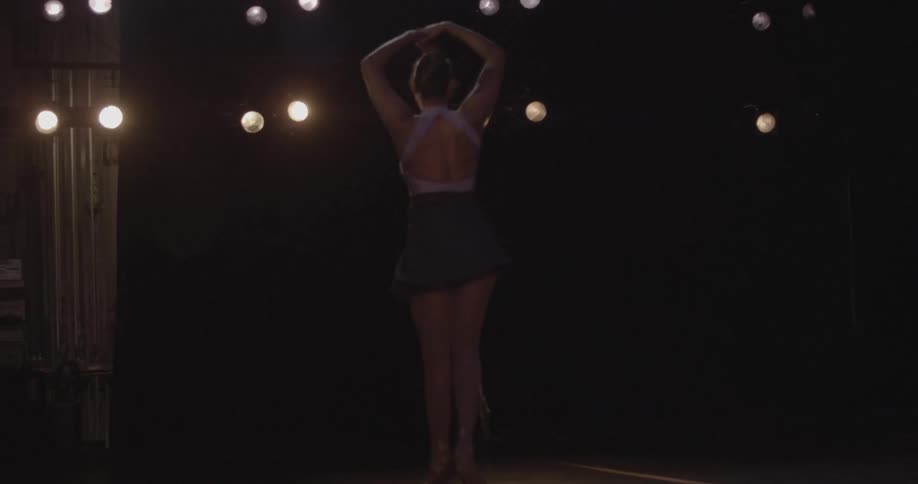 Woman dancing ballet on dimly lit theater stage