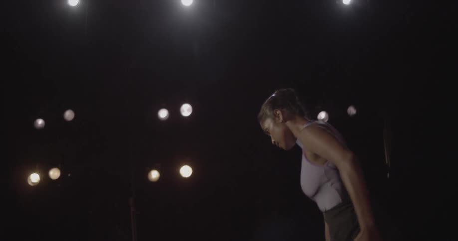 Woman performing ballet on a dimly lit theater stage