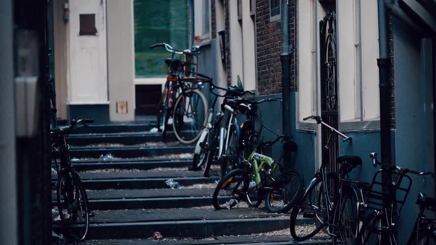 Moody static shot of bicycles parked along a narrow, stepped alley in a European city