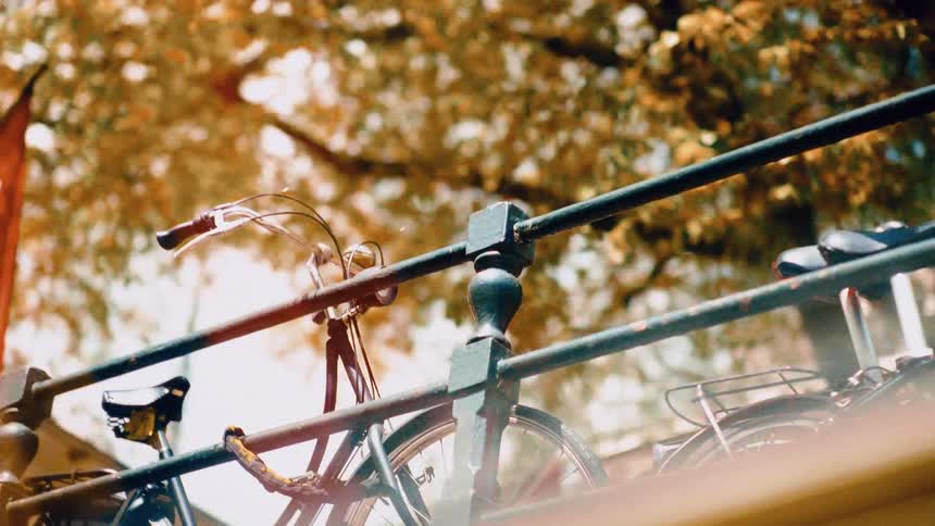 A dreamy low-angle slow pan reveals bicycles parked along a bridge railing in Amsterdam on a sunny autumn day