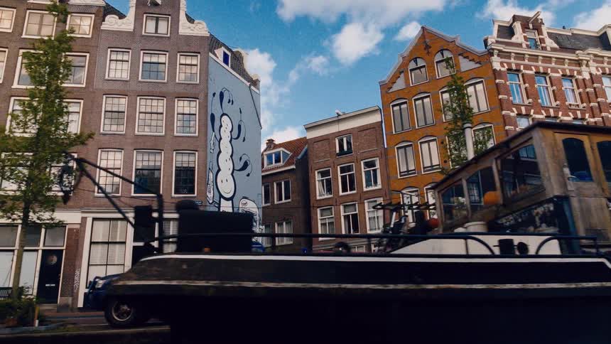 A slow-motion tracking shot from a boat reveals unique graffiti on the side of traditional Dutch canal houses in Amsterdam